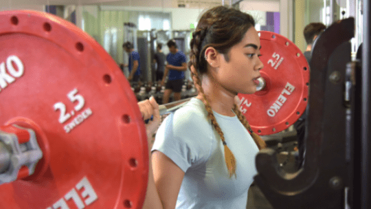 A female student lifting weights in the gateway gym